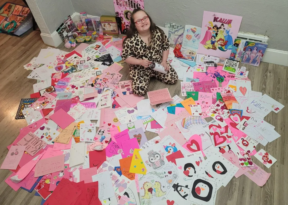 A girl sitting in a ring of pink handmade cards